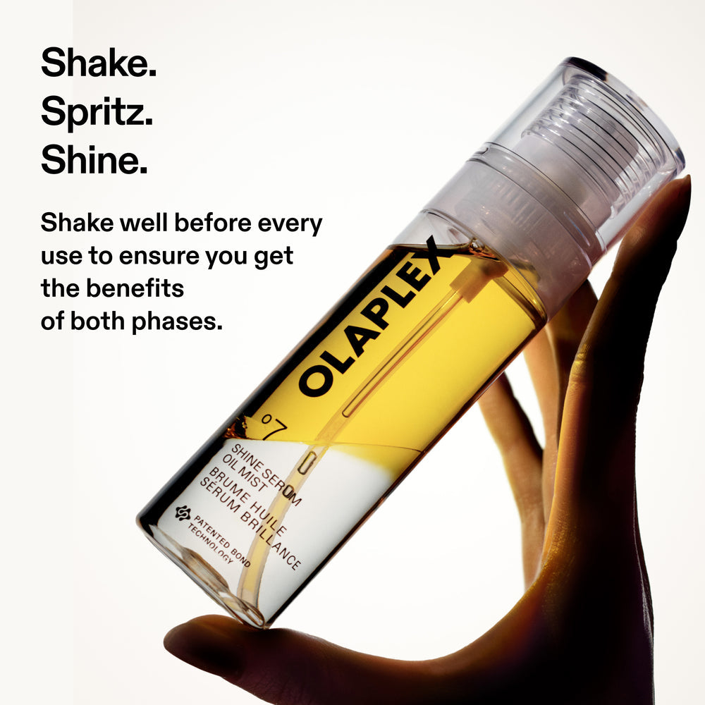 Hand holding Olaplex No.7 Shine Serum Oil Mist bottle with shake spritz shine instructions for the bi-phase formula