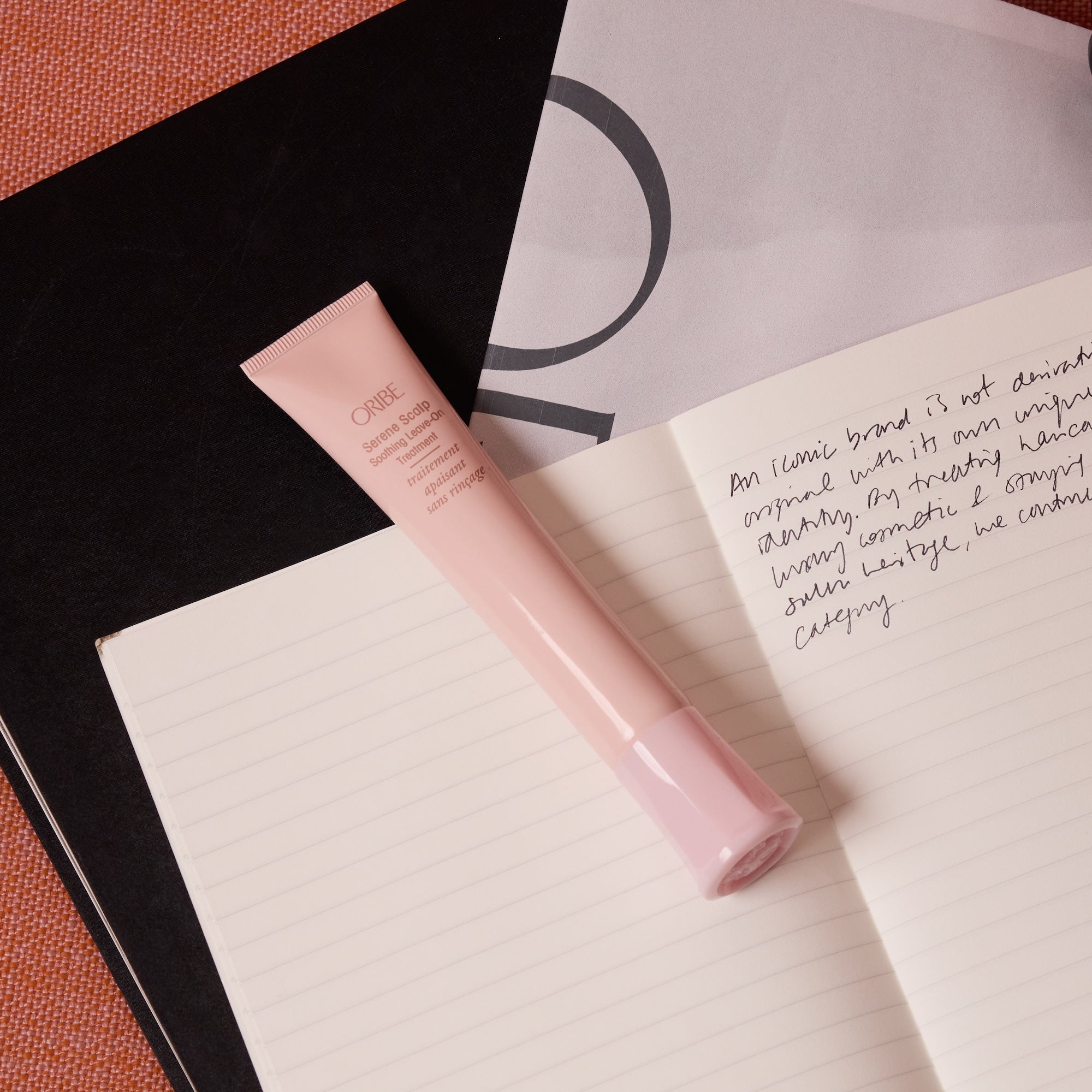 Oribe Serene Scalp Soothing Leave-On Treatment tube, editorial flat lay