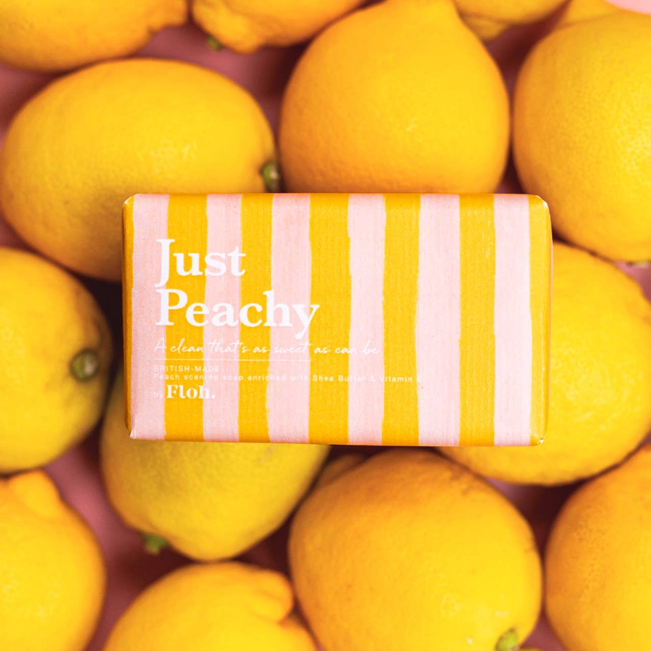 Toasted Crumpet Just Peachy 190g soap bar in peach striped wrap on a bed of citrus fruit
