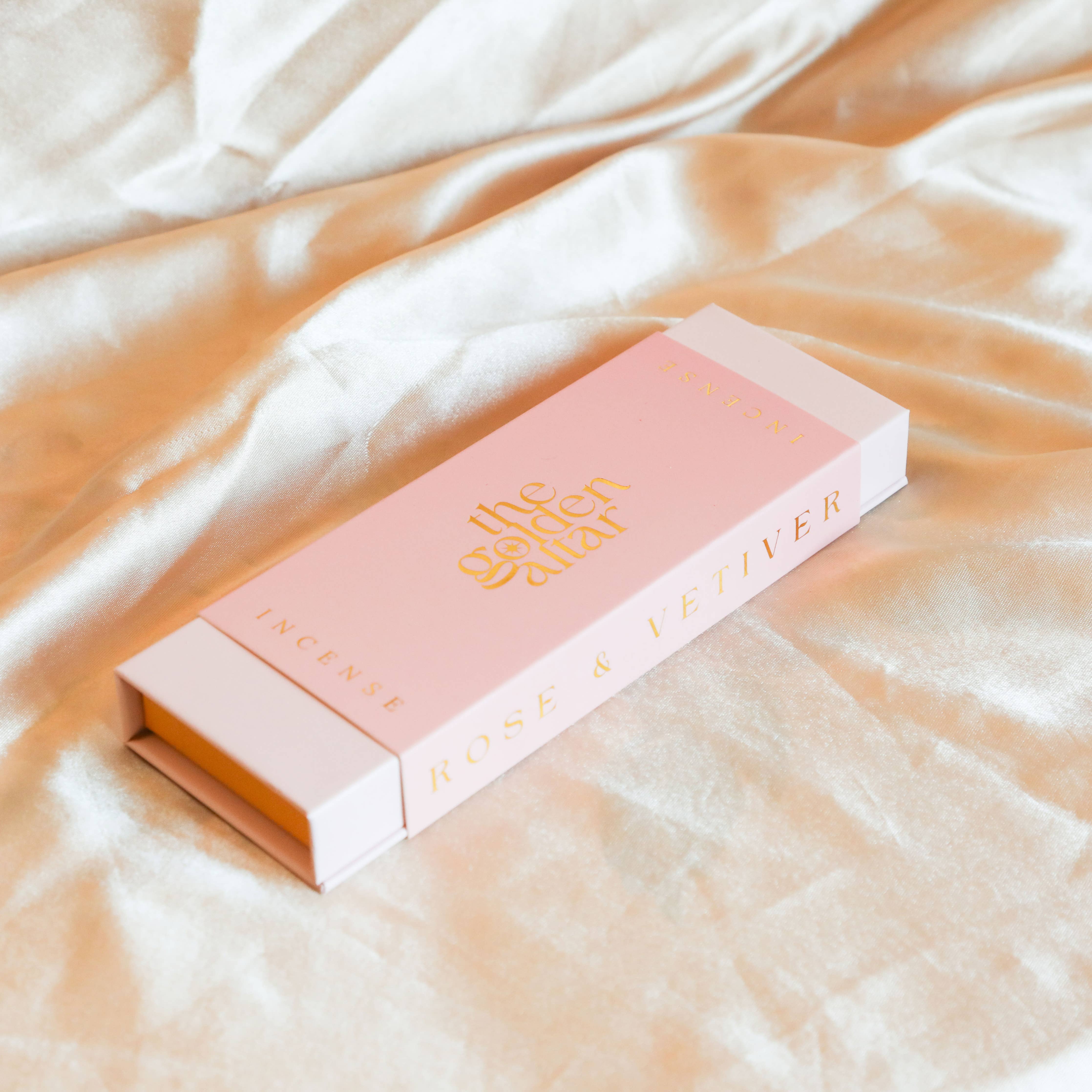 Pink and gold incense box on a soft fabric background