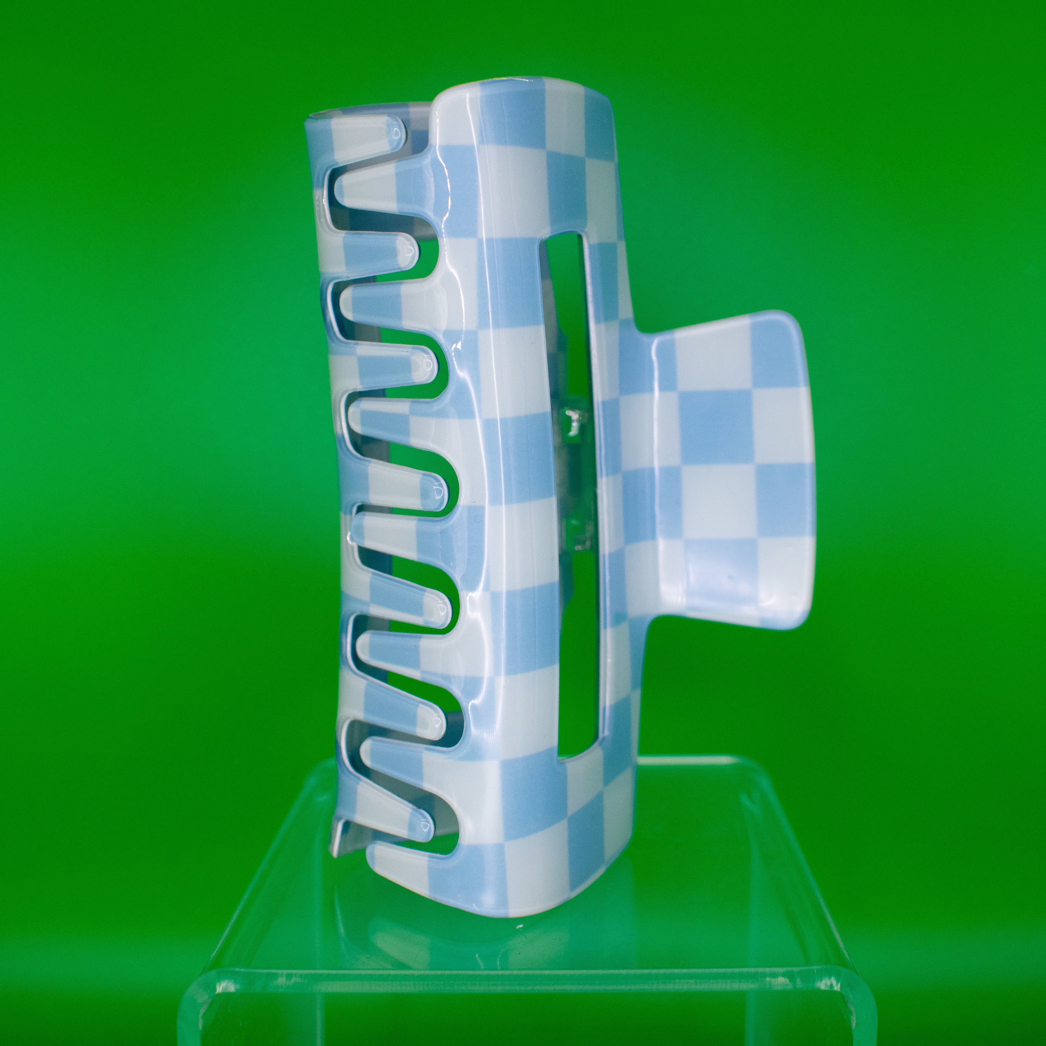 A large blue and white checkered retro claw clip displayed on a green background.
