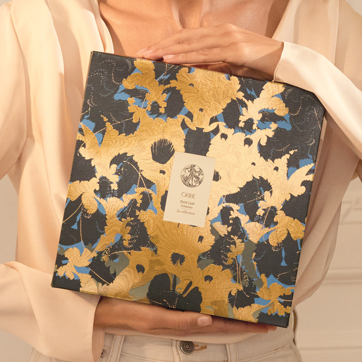 Person holding the Gold Lust Collection Holiday Pack from Oribe
