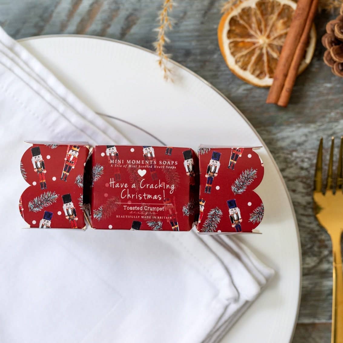 Toasted Crumpet Nutcracker boxed mini soaps in a red cracker shaped gift box on a white plate