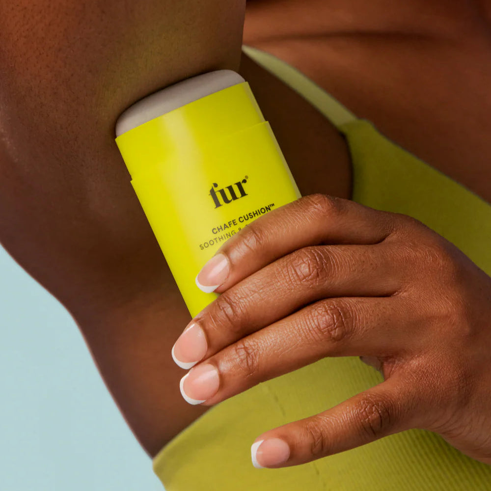Person holding a yellow bottle labeled 'fur' against a blurred background