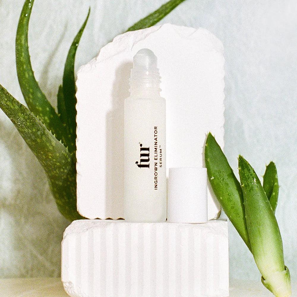 Fur Ingrown Eliminator Serum Rollerball bottle on a light background with green leaves.
