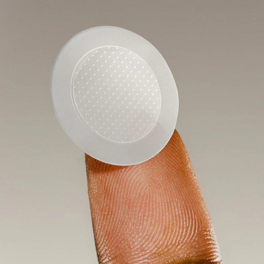 Clear adhesive patch on a finger against a neutral background
