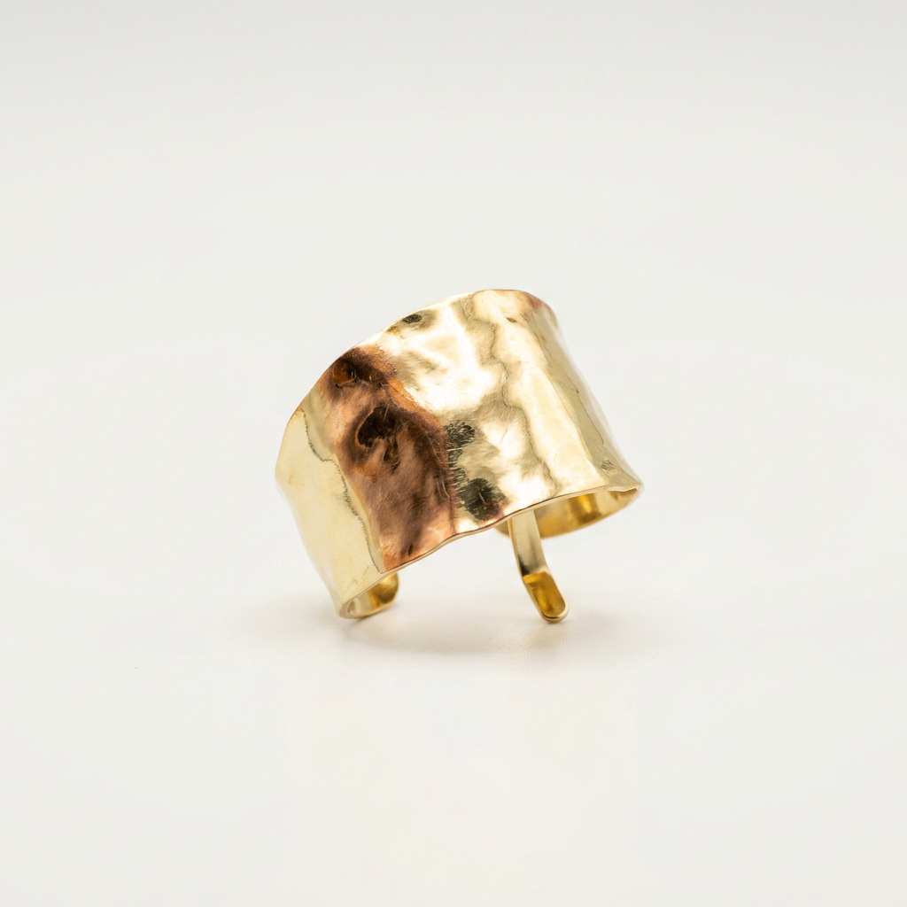 Gold ponytail cuff with a textured surface on a light gray background