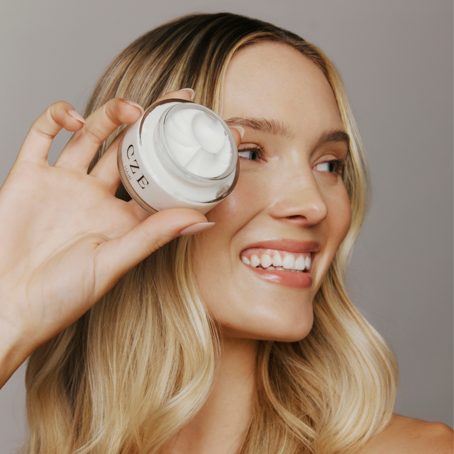 Model holding CZE Style Defining Creme lightweight anti-frizz styling cream