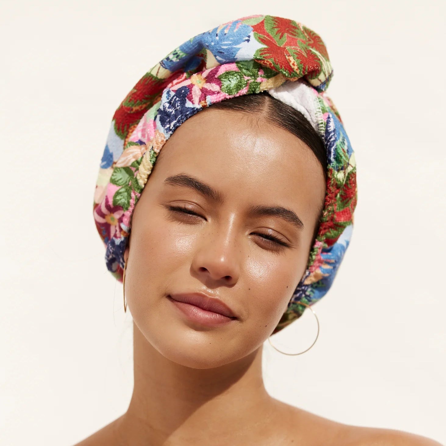 Woman wearing a colorful floral Louvelle towel wrap on a white background