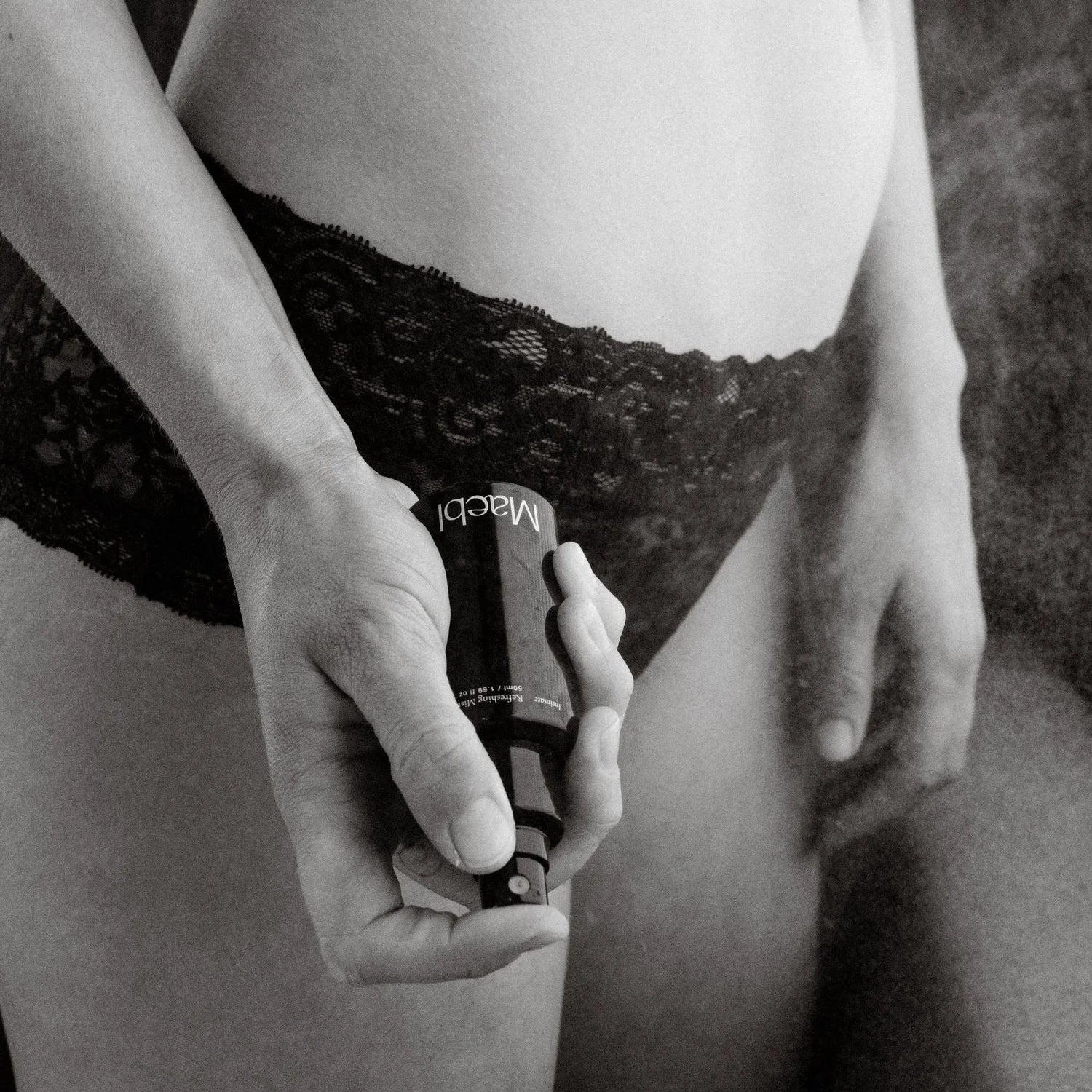 Person holding a bottle of Maebl Intimate Refreshing Mist in black and white.