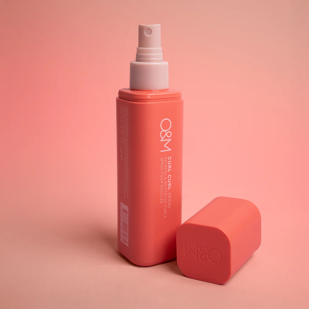 Red O&M Curl Curl spray bottle with a white nozzle on a pink background
