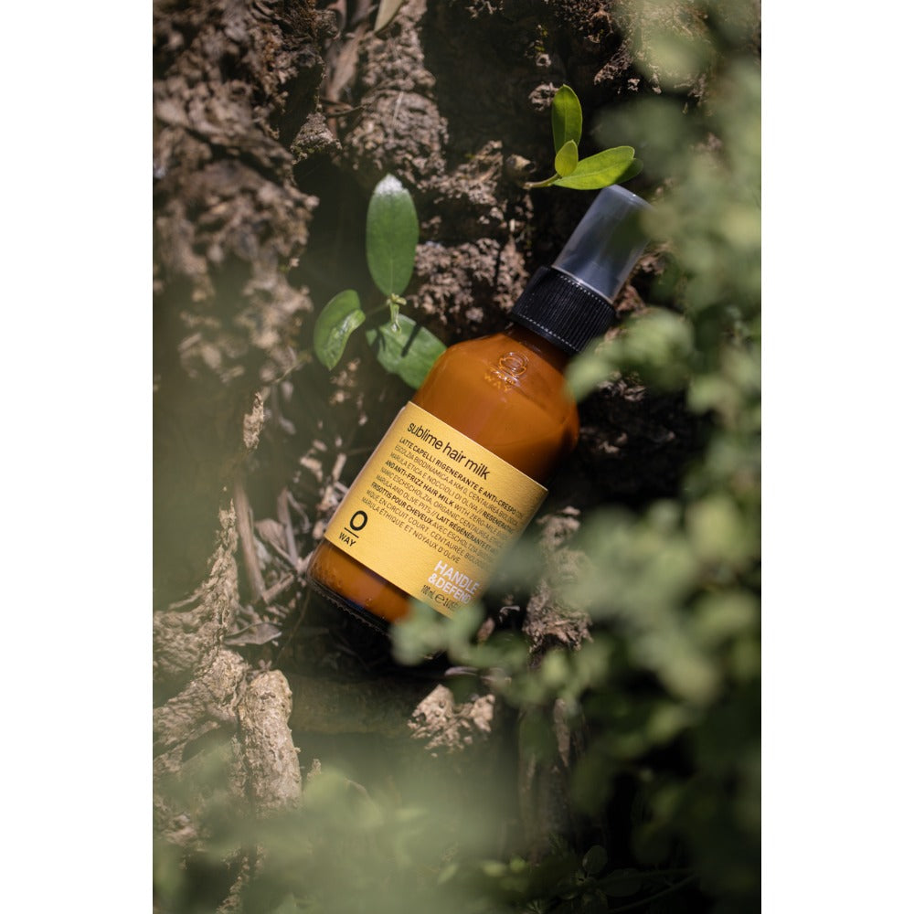 Oway Sublime Hair Milk 100ml bottle amongst greenery