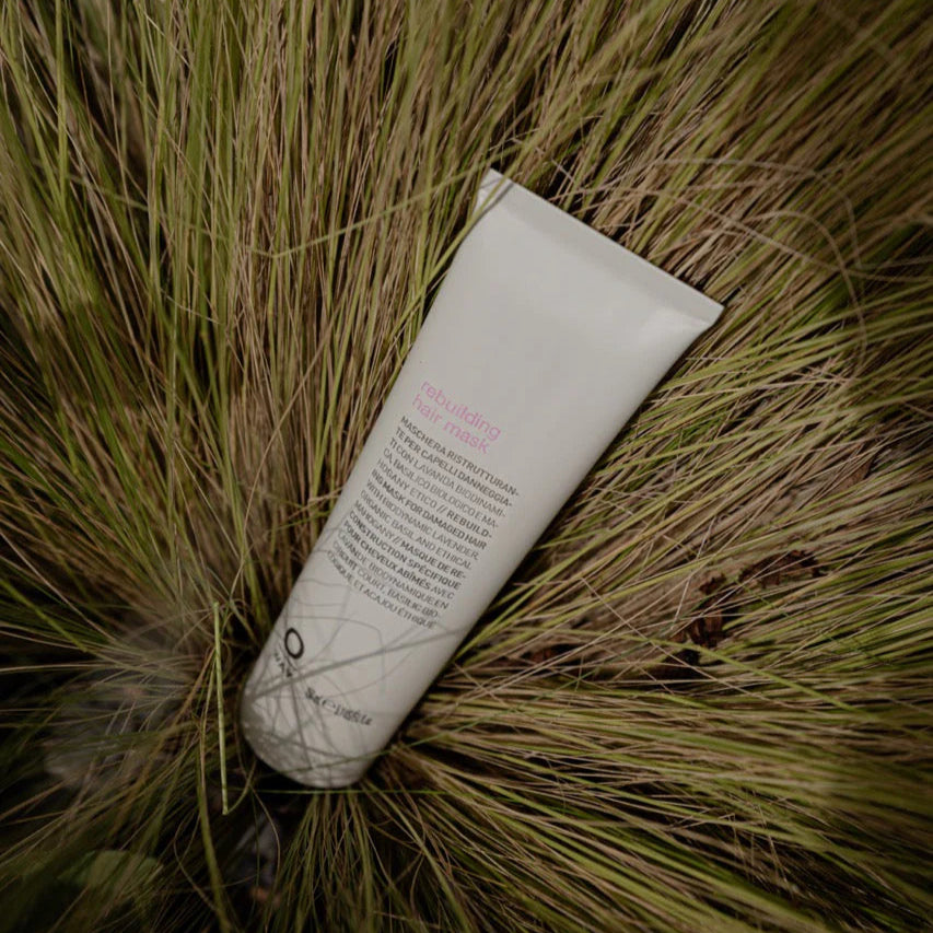 Tube of Oway Rebuilding hair mask lying on grass