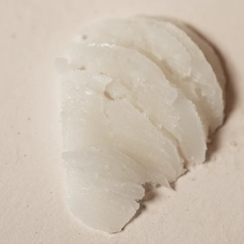 Close-up of a scoop of Oway Precious Wax on a sandy coloured surface