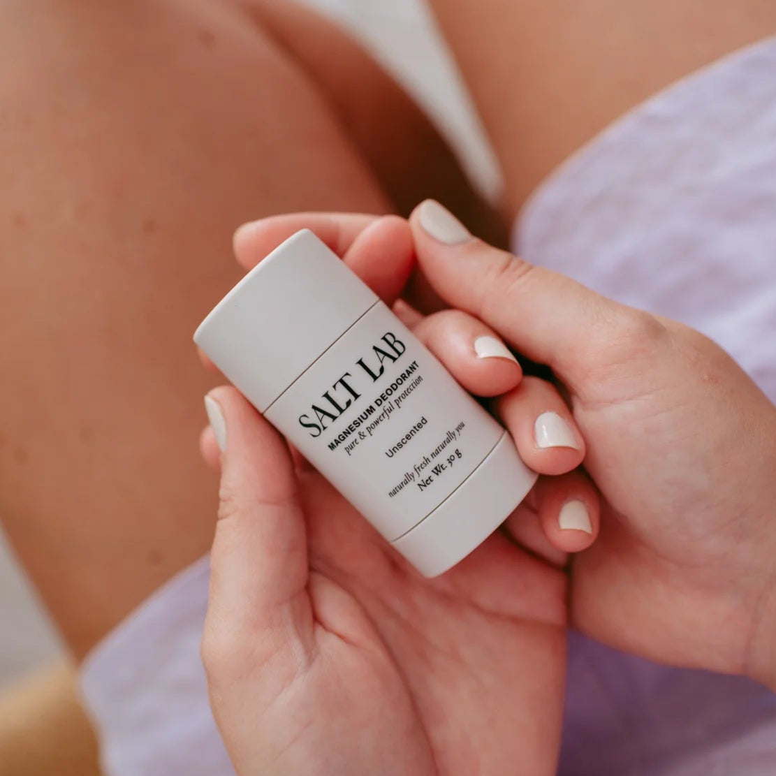 Person holding a 'Salt Lab Magnesium Deodorant' product with a blurred background