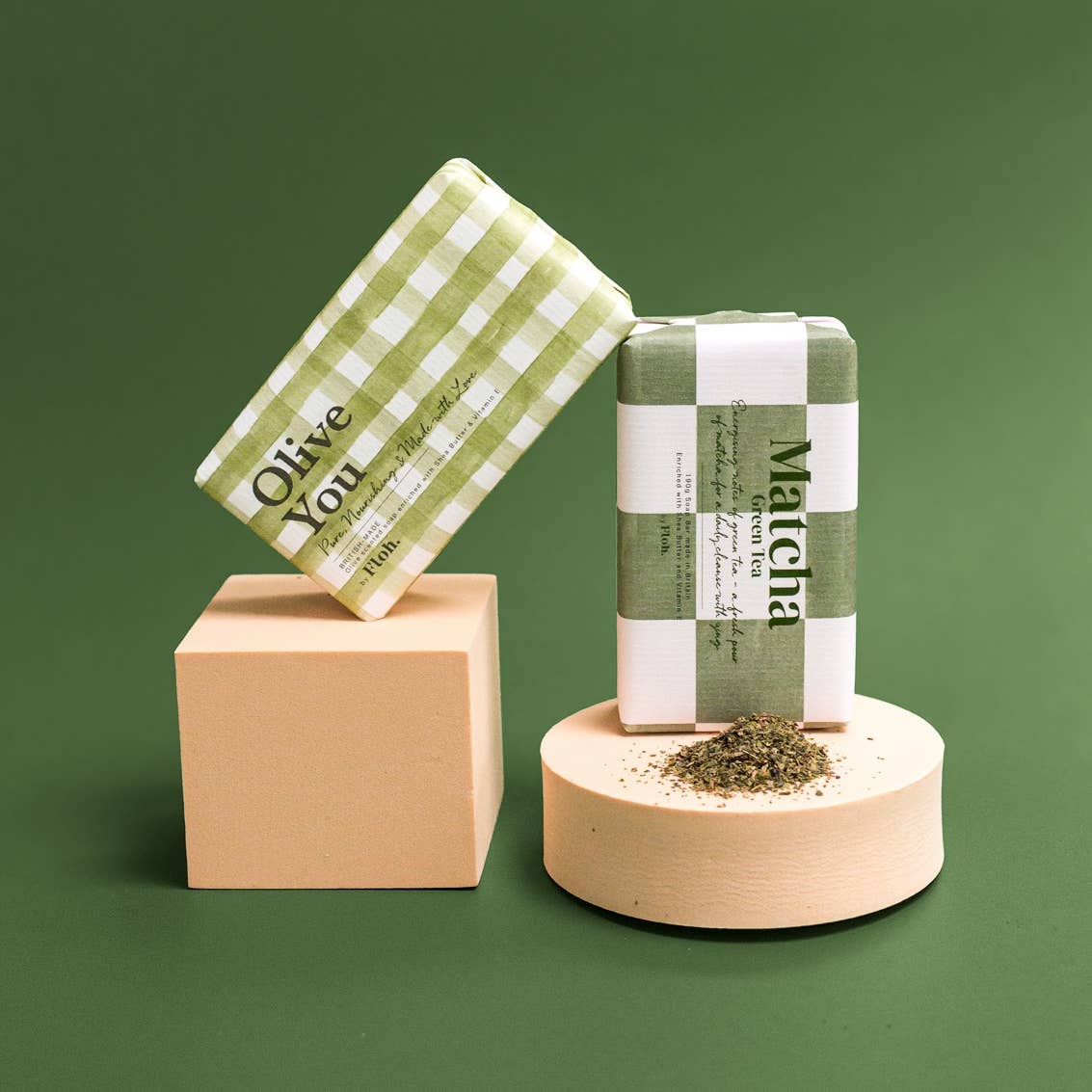 Toasted Crumpet Olive You soap bar styled on plinths against a green background