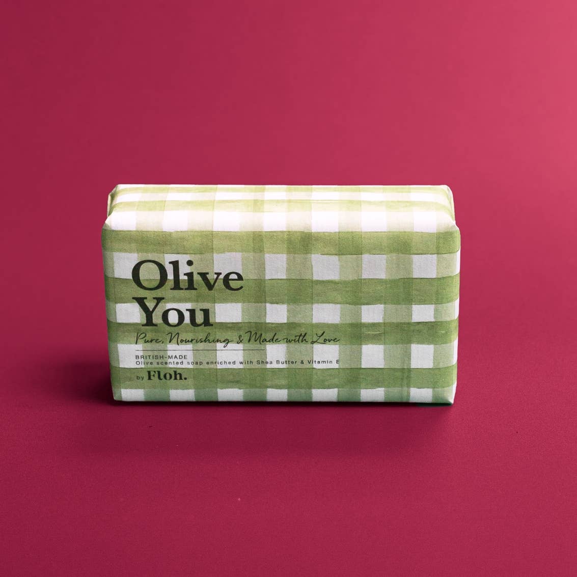 Toasted Crumpet Olive You 190g soap bar standing upright on a deep crimson background