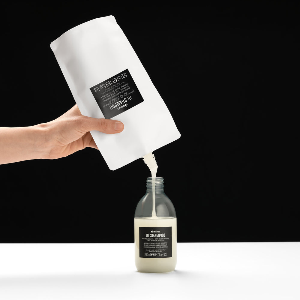Davines Oi Shampoo 500ml Refill being poured into bottle — Sable Boutique NZ