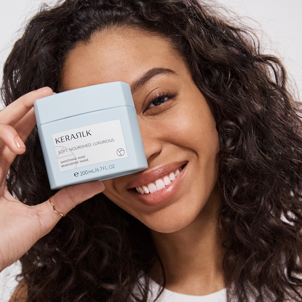 Model holding Kerasilk Smoothing Mask jar for coarse, frizzy hair