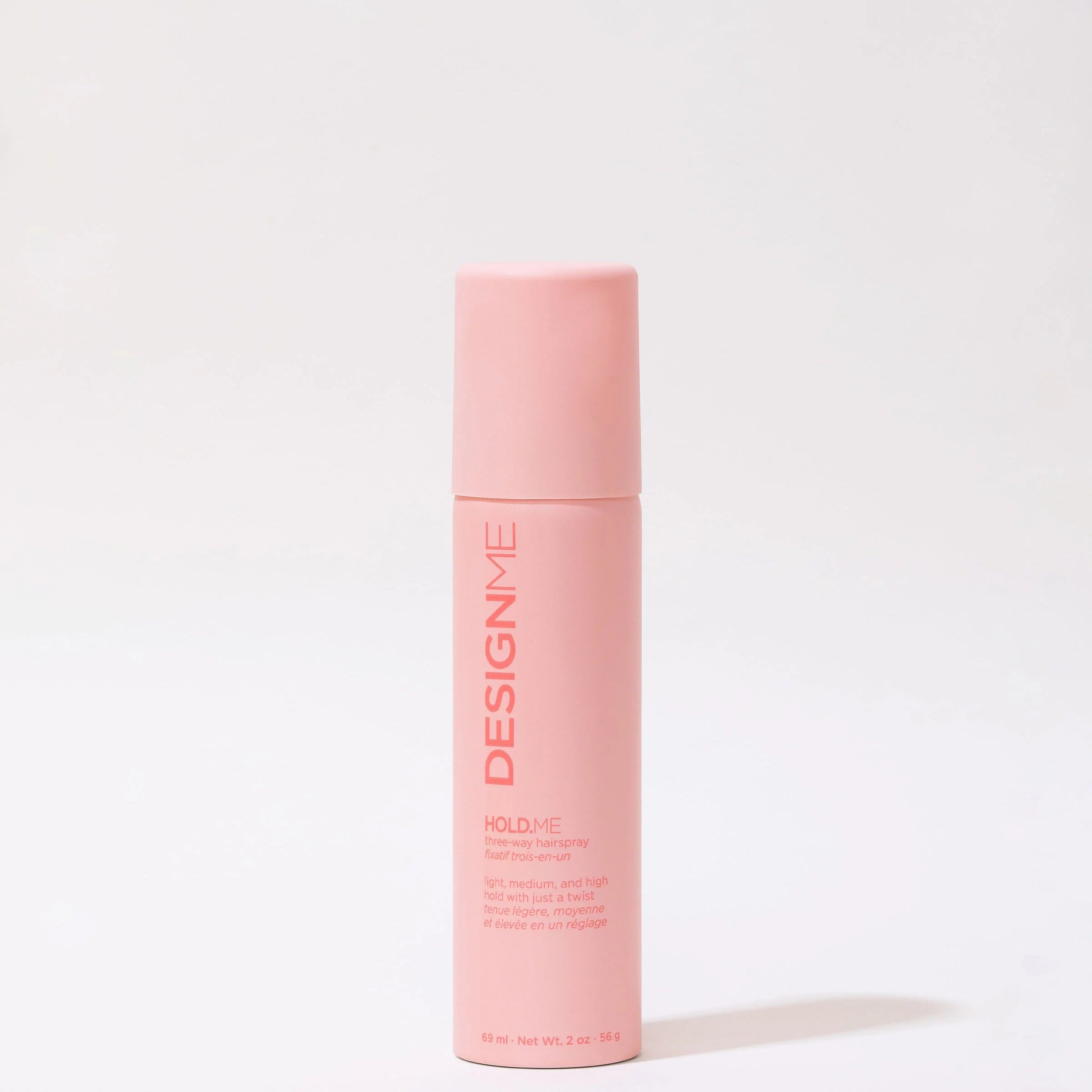 Pink bottle of 'Design Me Three Way Hairspray' on a white background
