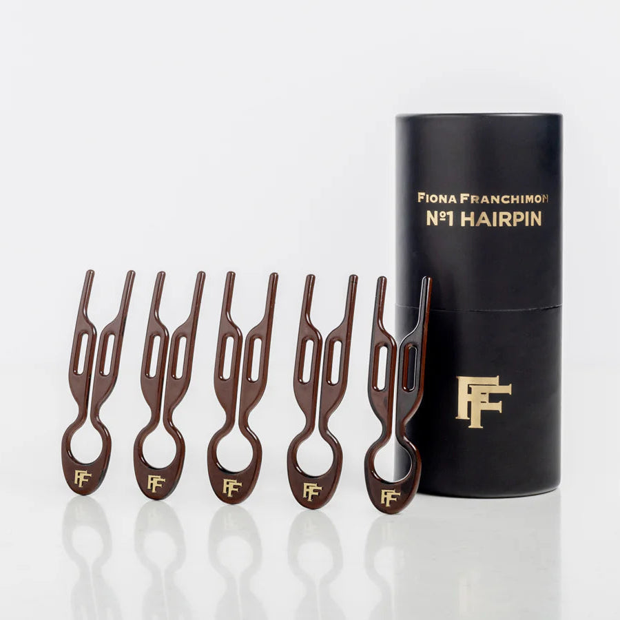 Set of hairpins with a black cylindrical container on a white background