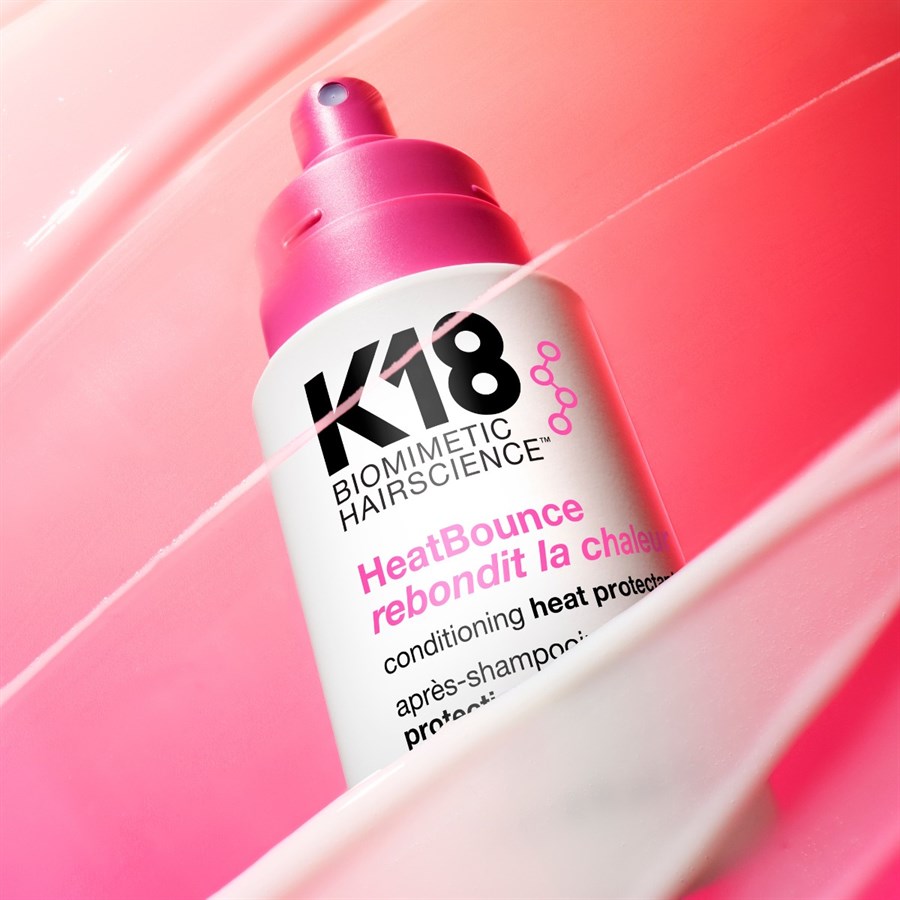 K18 BHeatBounce spray bottle on a pink background