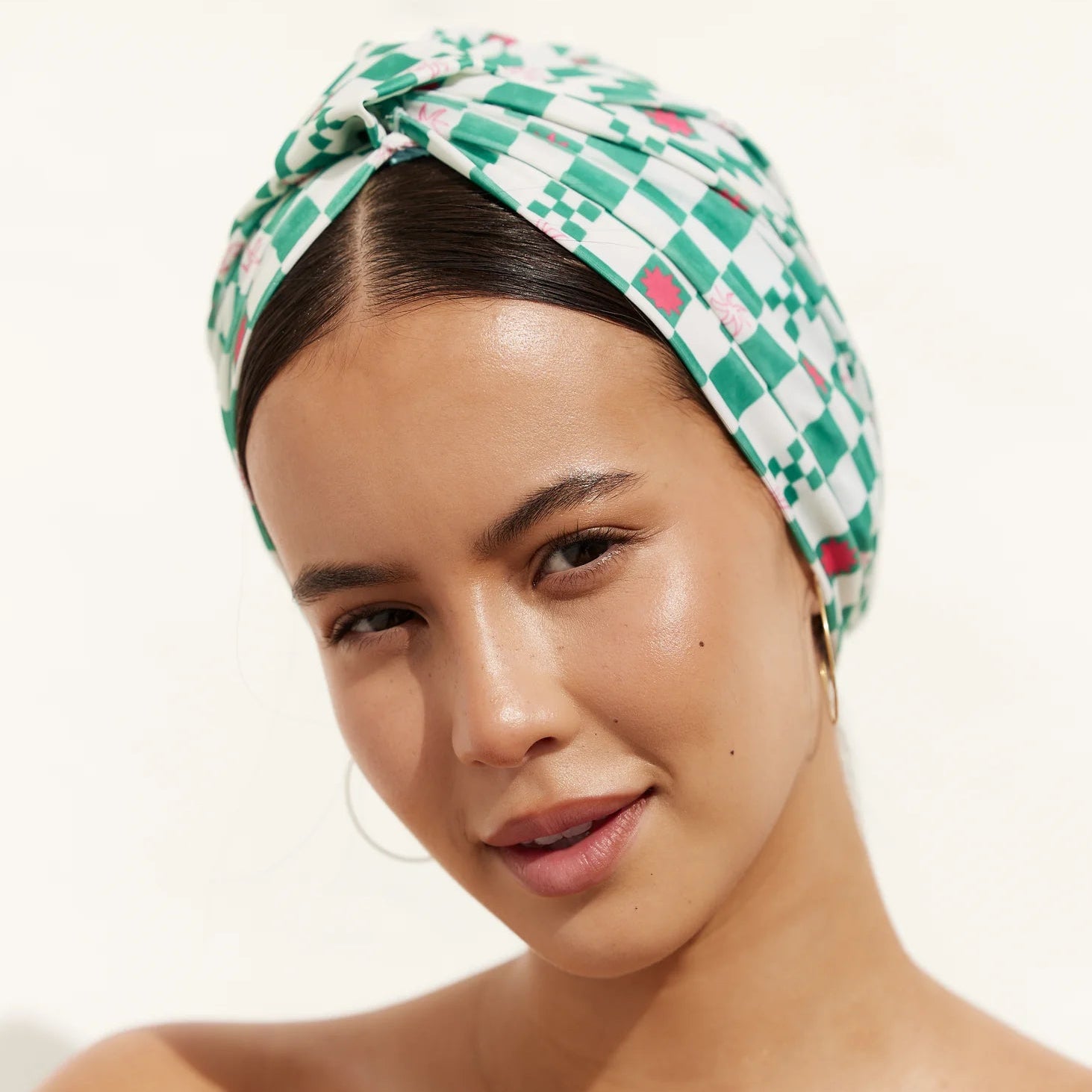 Woman wearing a green patterned Louvelle Shower Cap on a white background