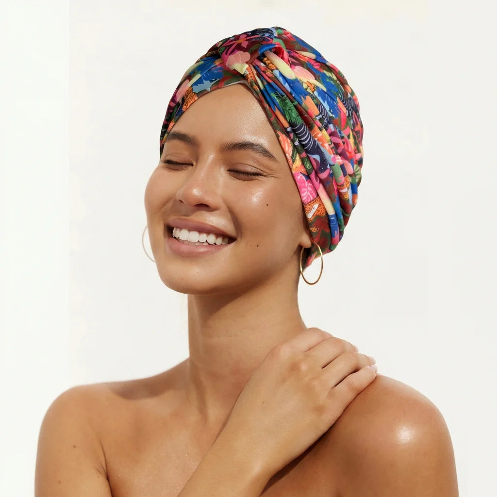 Woman wearing a colorful Louvelle Shower Cap on a plain background