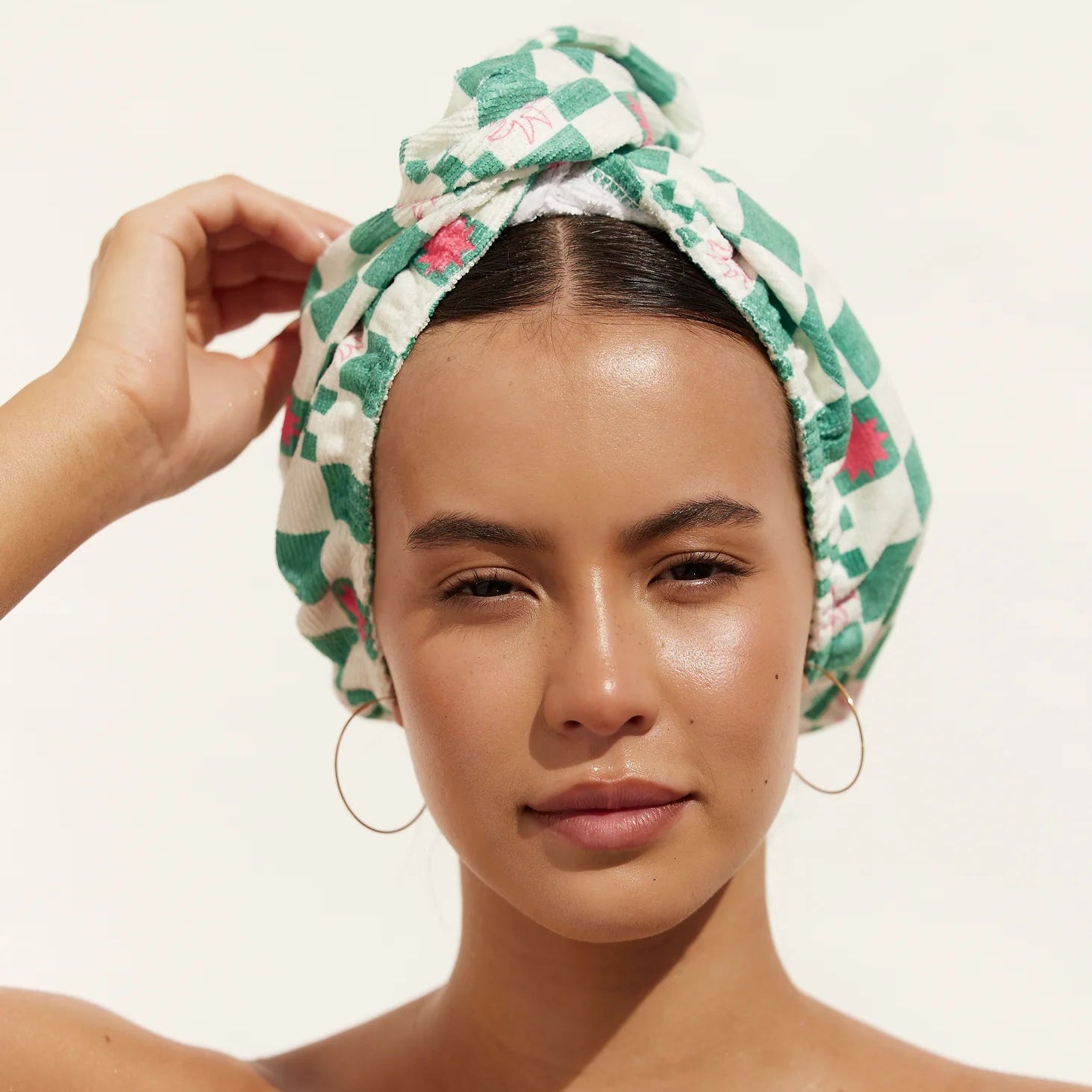 Woman wearing a green patterned towel on her head against a white background