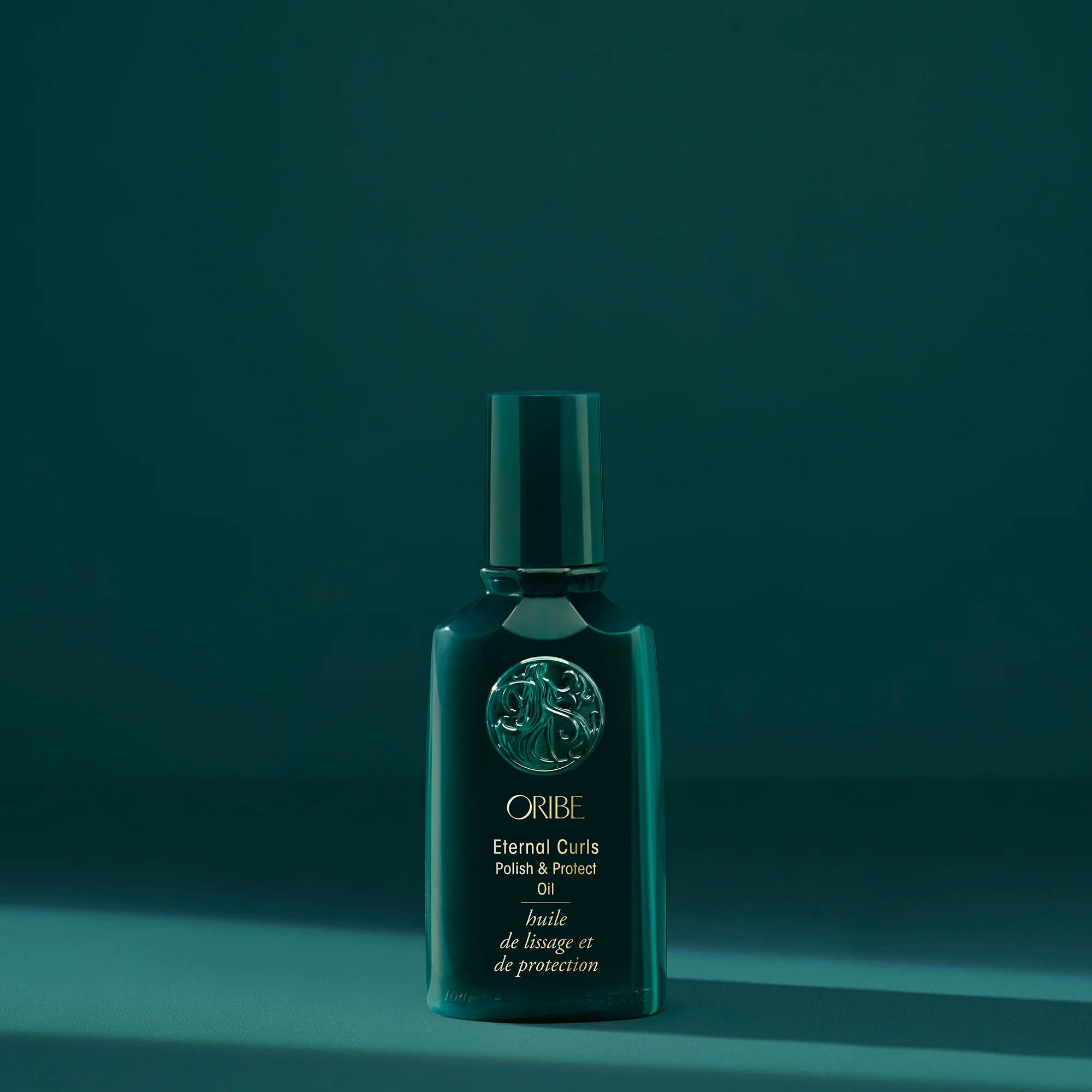 A bottle of Oribe Eternal Curls Polish and Protect Oil on a green background
