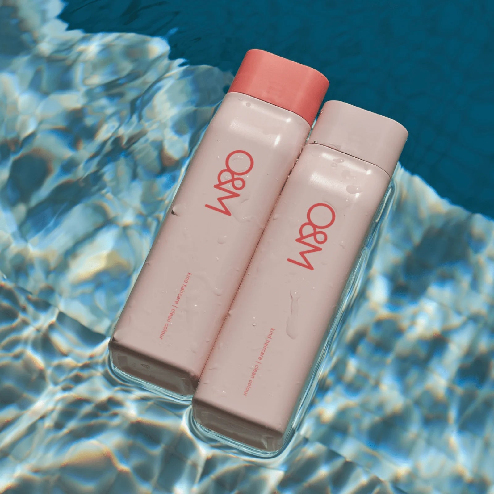Bottles of a O&M Curl Curl Shampoo and Conditioner on a water surface