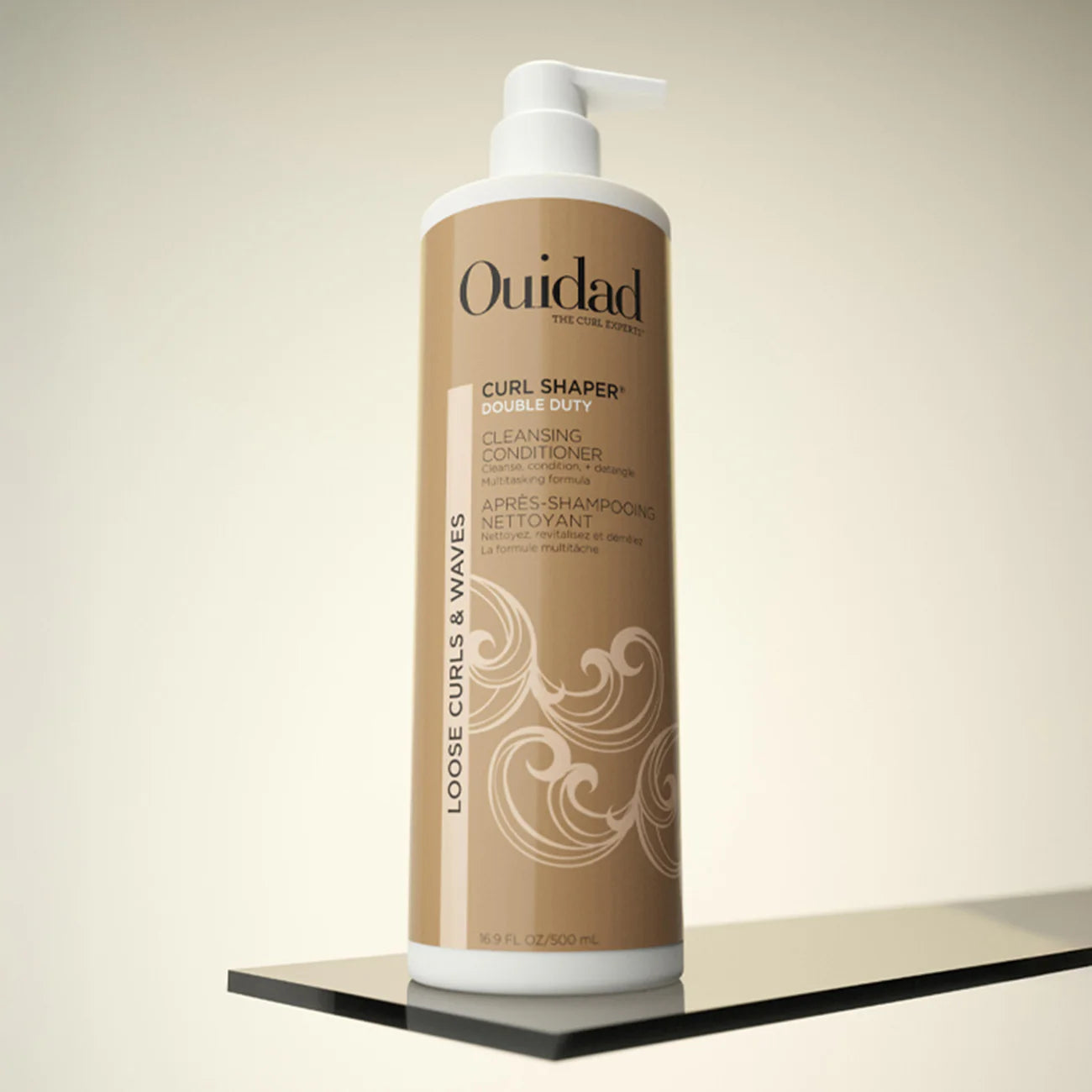 Ouidad Curl Shaper Double Duty Cleansing Conditioner bottle on a beige background
