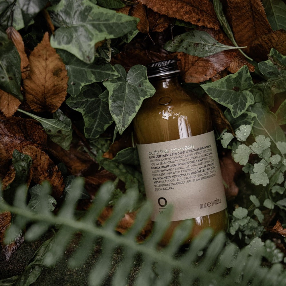 Oway Curly Hair Co-Wash bottle among ferns