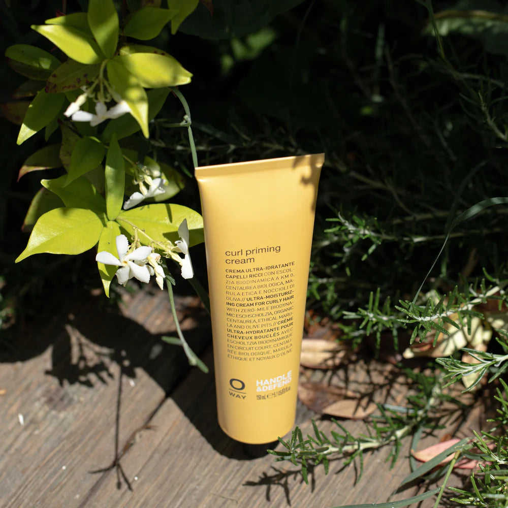 Tube of Oway curl priming cream on a wooden surface with greenery