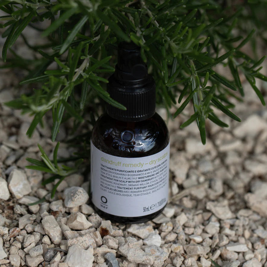 Bottle of Oway's dandruff remedy on a stone surface with greenery