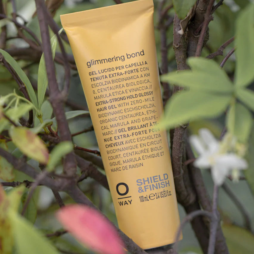 Yellow tube of 'Oway Glimmering Bond' product among green leaves