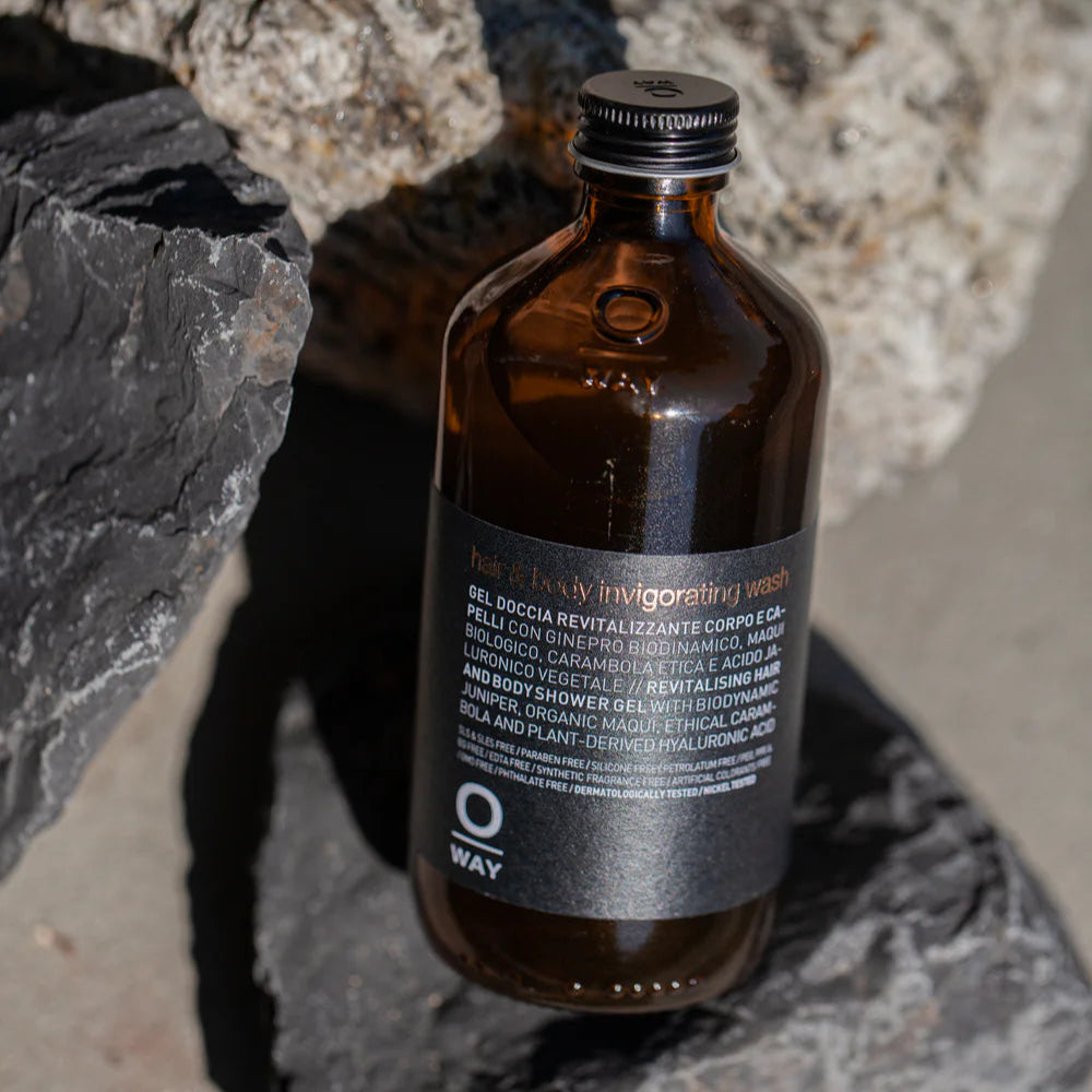 Brown bottle of Oway Hair & Body Invigorating Wash on a stone surface.