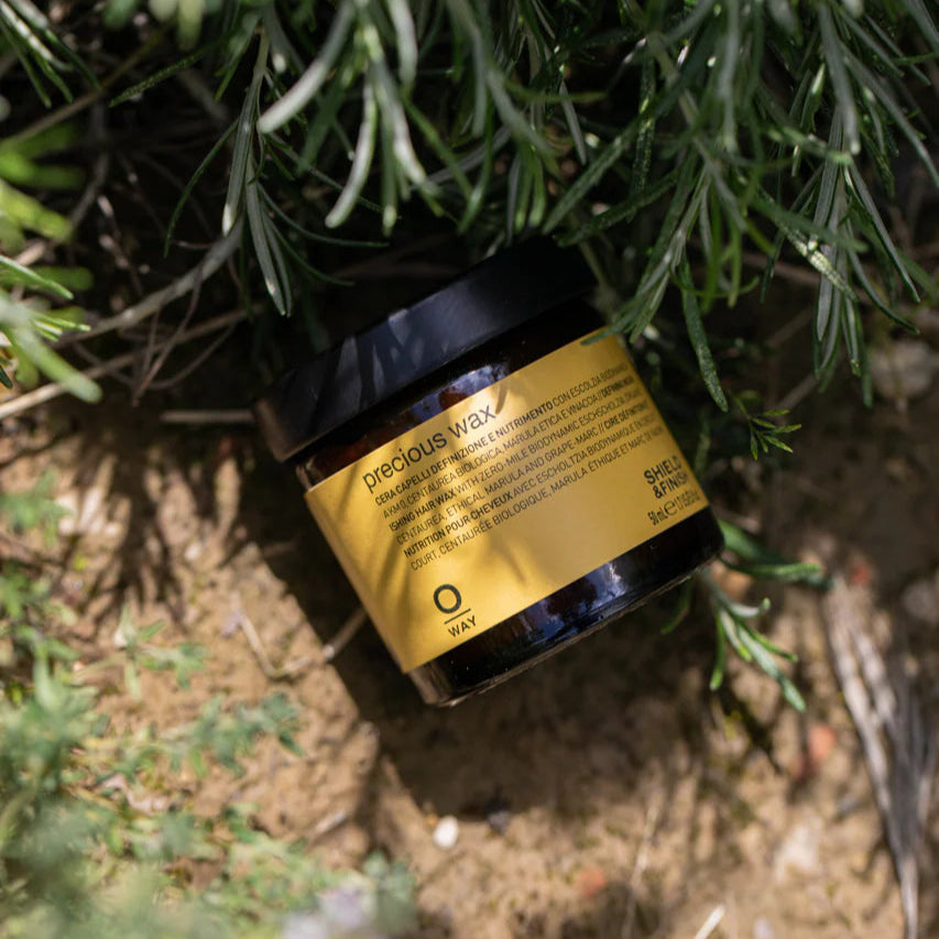 A container of Oway precious wax stylised photo on ground with grass