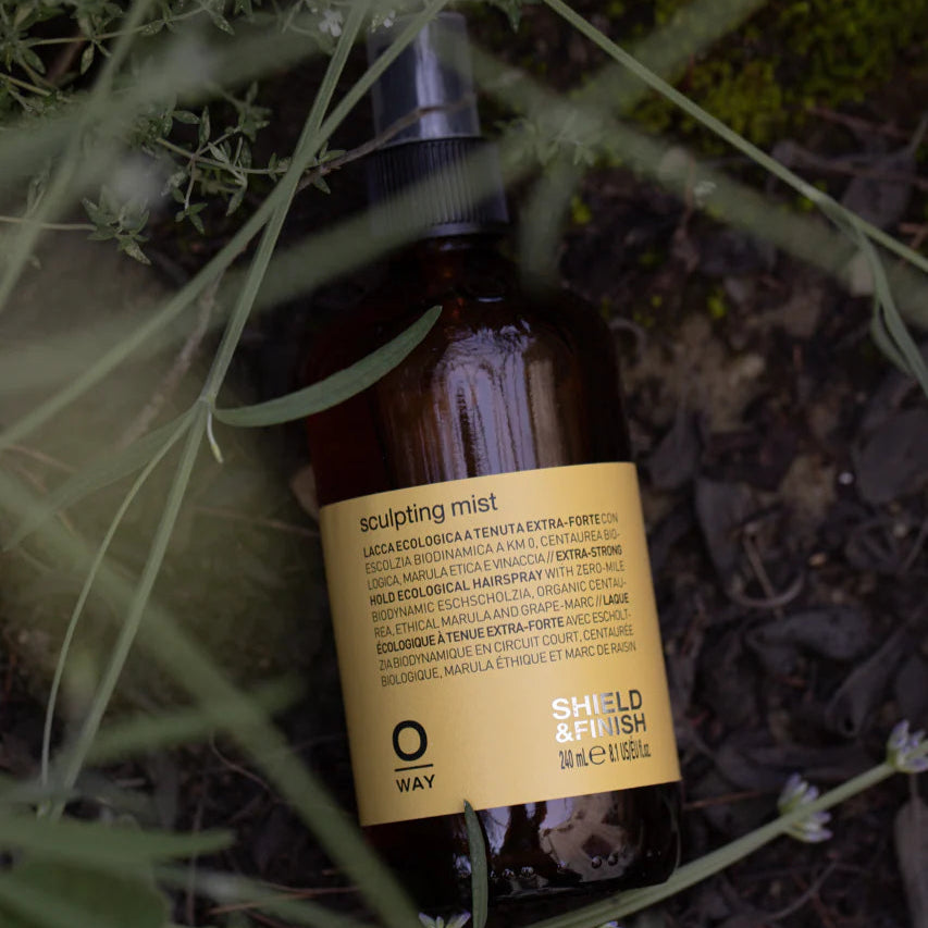 Brown bottle with yellow Oway Sculpting Mist label on a natural background