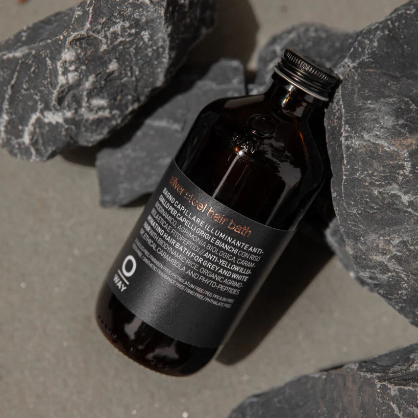 A bottle of Oway Silver Steel Hair Bath on a gray stone surface