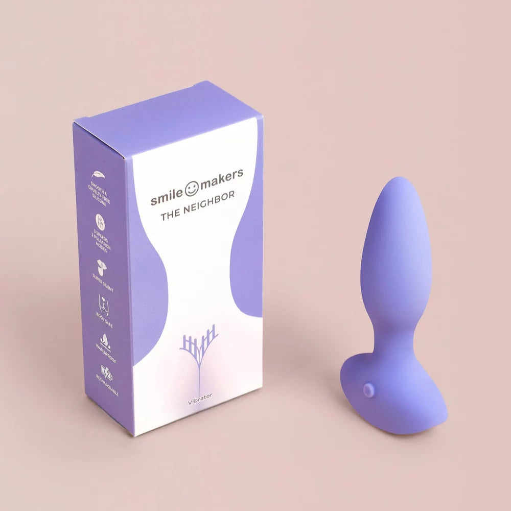 Purple silicone butt plug with 'smile makers' packaging on a beige background