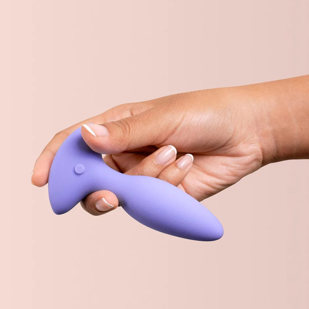 Hand holding a purple silicone tool against a beige background