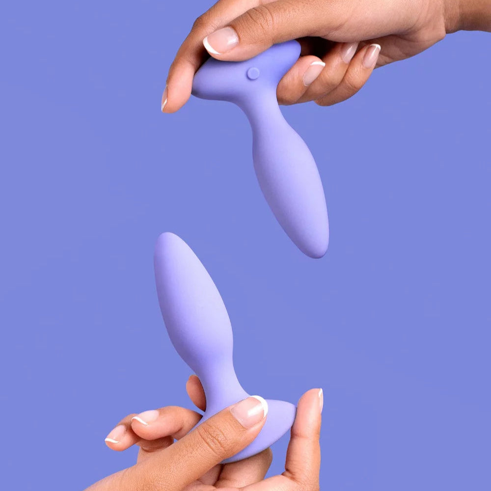 Two hands holding a purple electronic device against a solid background