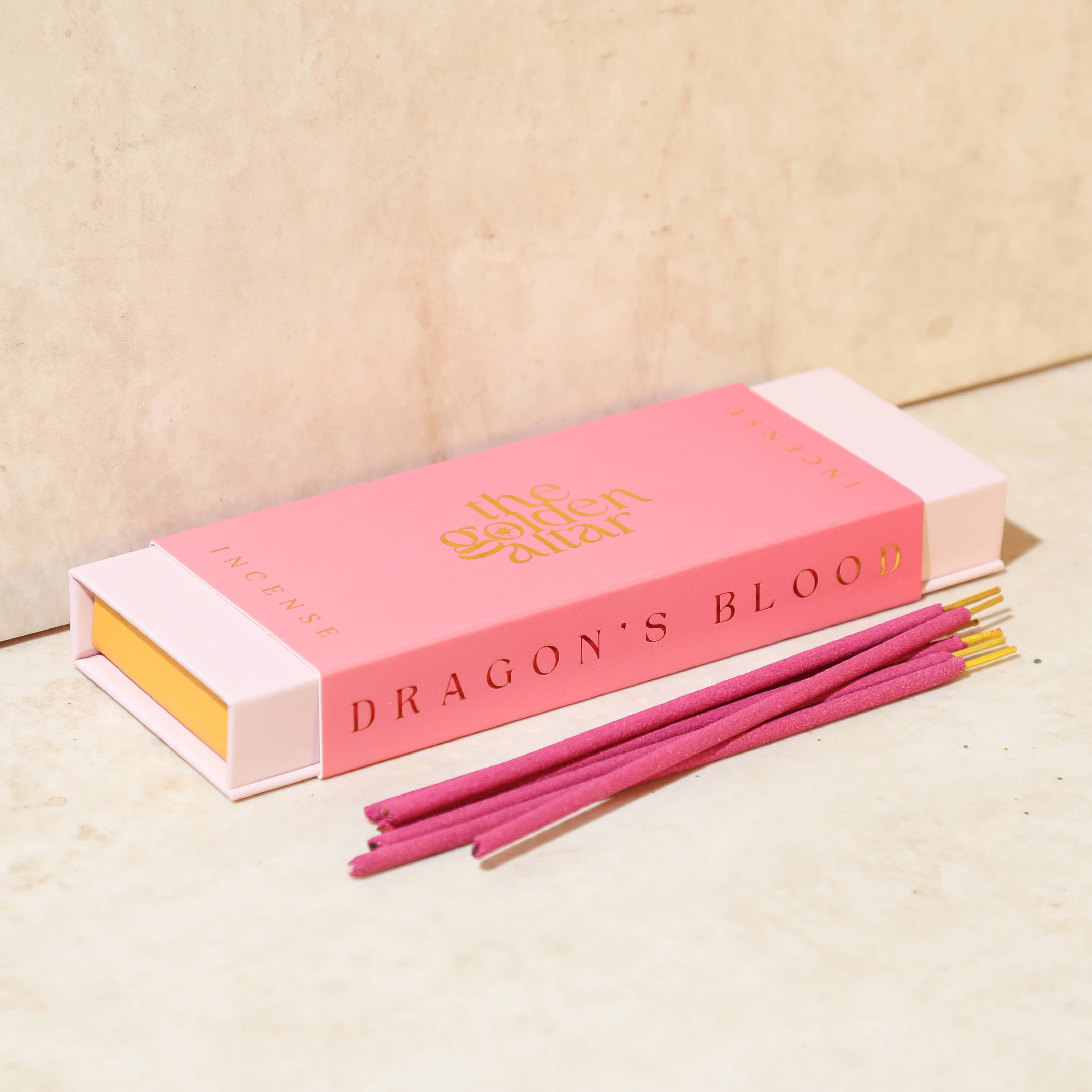Pink incense sticks with packaging labeled The Golden Altar with 'Dragon's Blood' scent on a beige background