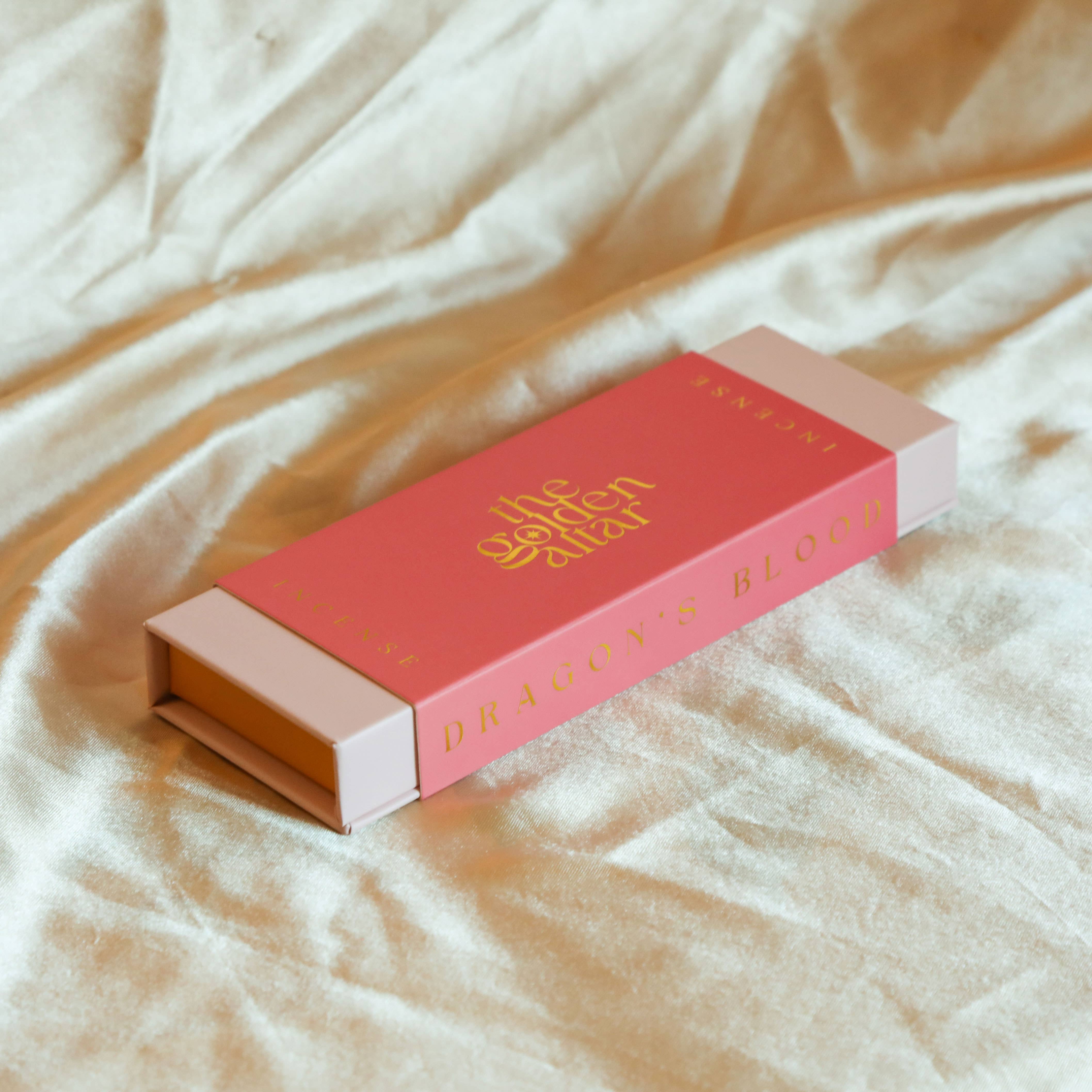 Red and pink box with gold text on a beige fabric background