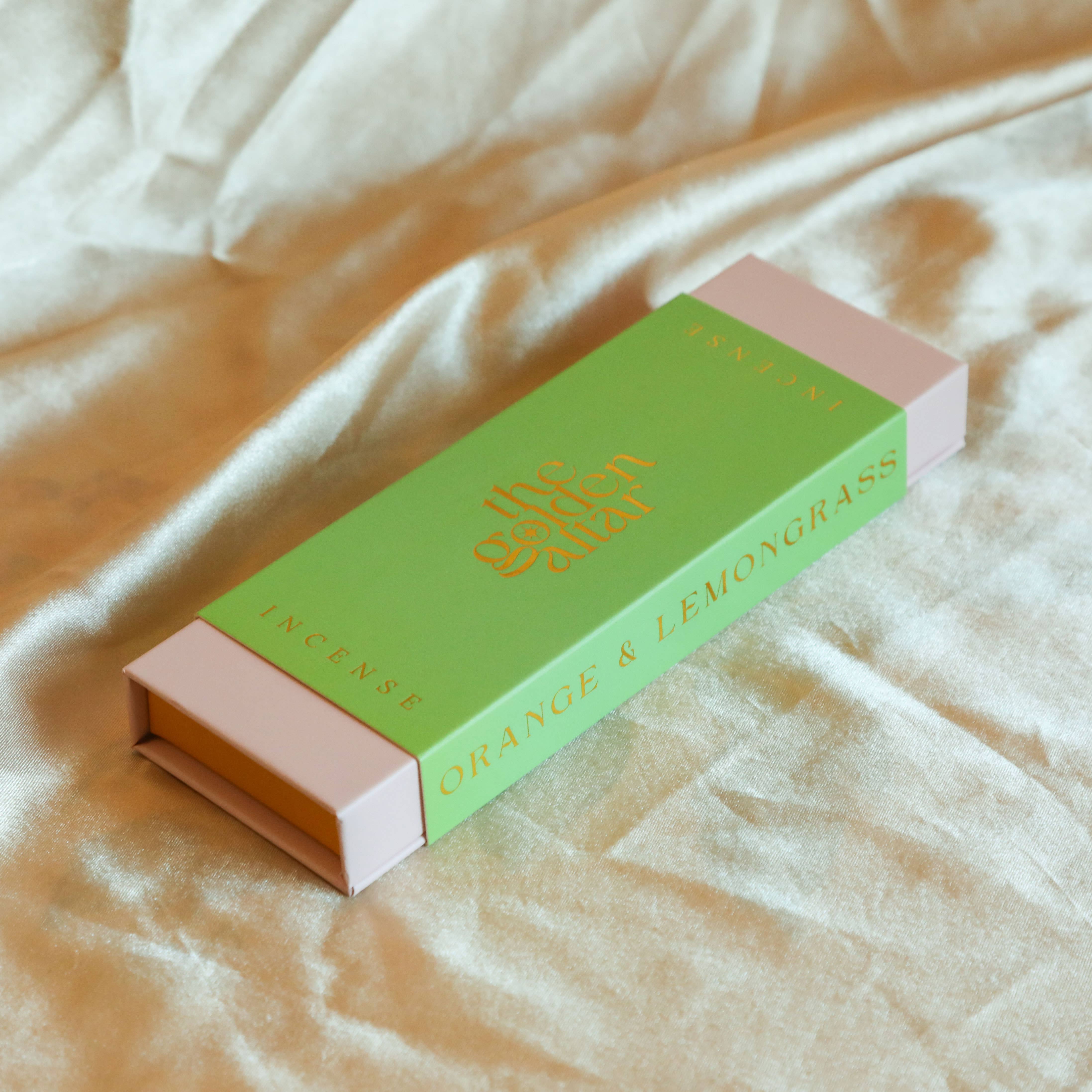 The Golden Altar Incense box labeled 'Orange & Lemongrass' on a beige fabric background